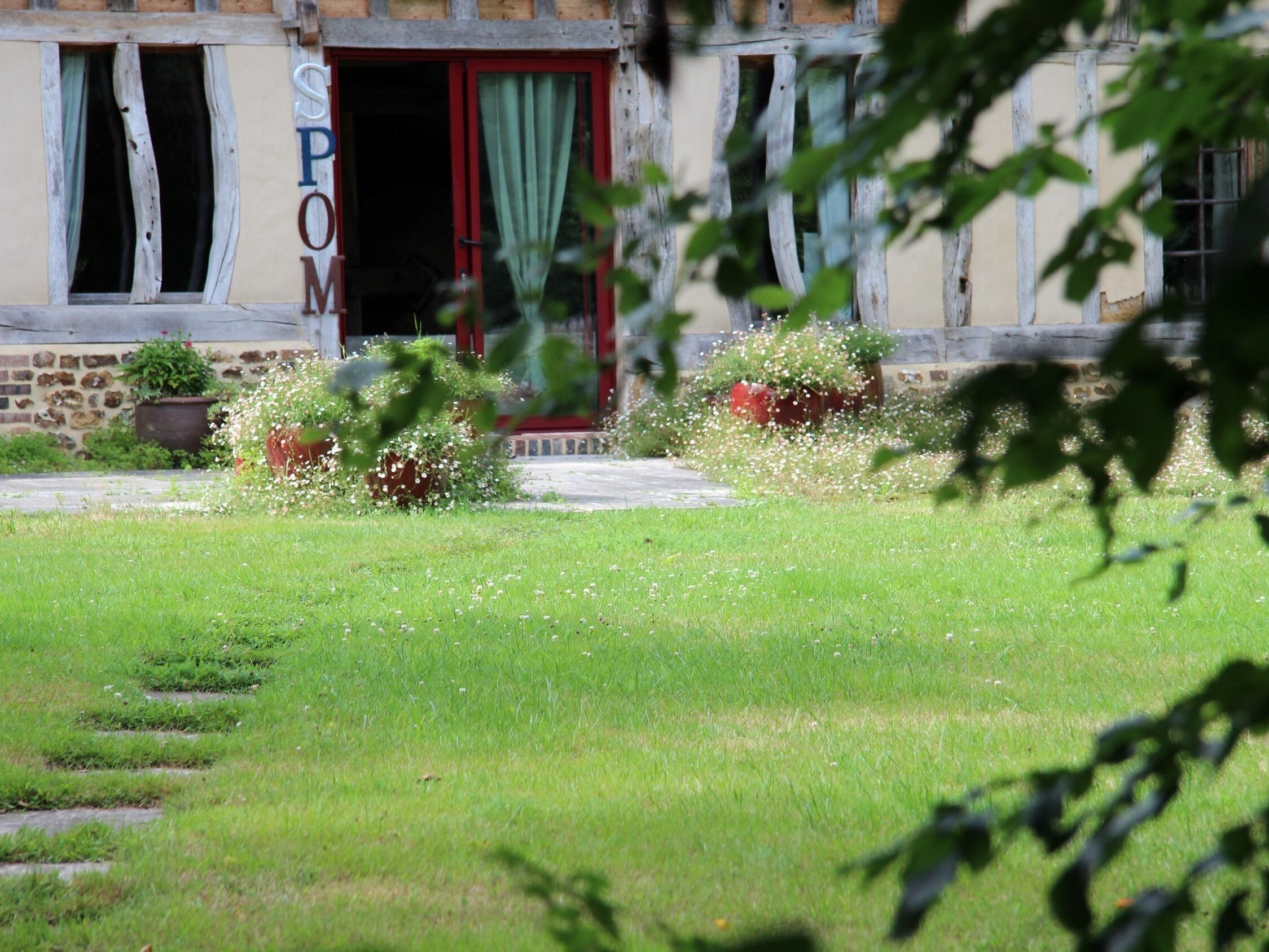 A building with a red door, a sign with letters, and a well-maintained lawn with flowers.