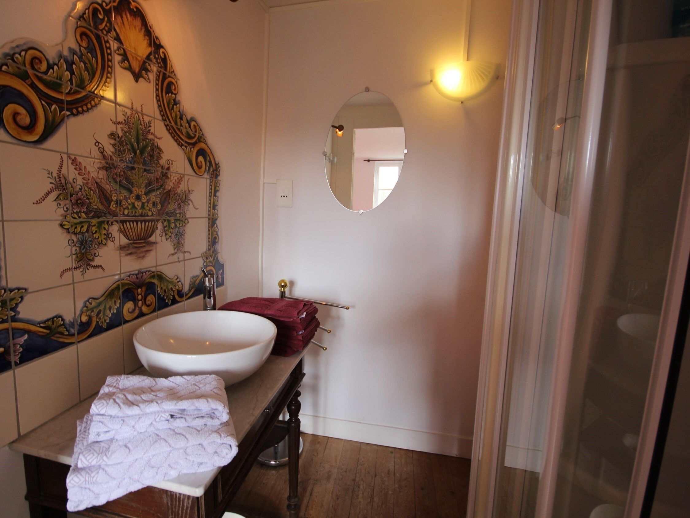 Une salle de bain avec un lavabo blanc, un miroir et des carreaux décoratifs.