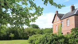 A brick house with a well-maintained lawn and dense greenery in the background. - Le Pommenial de la Hérissonnière (Saint-Aubin-de-Bonneval)