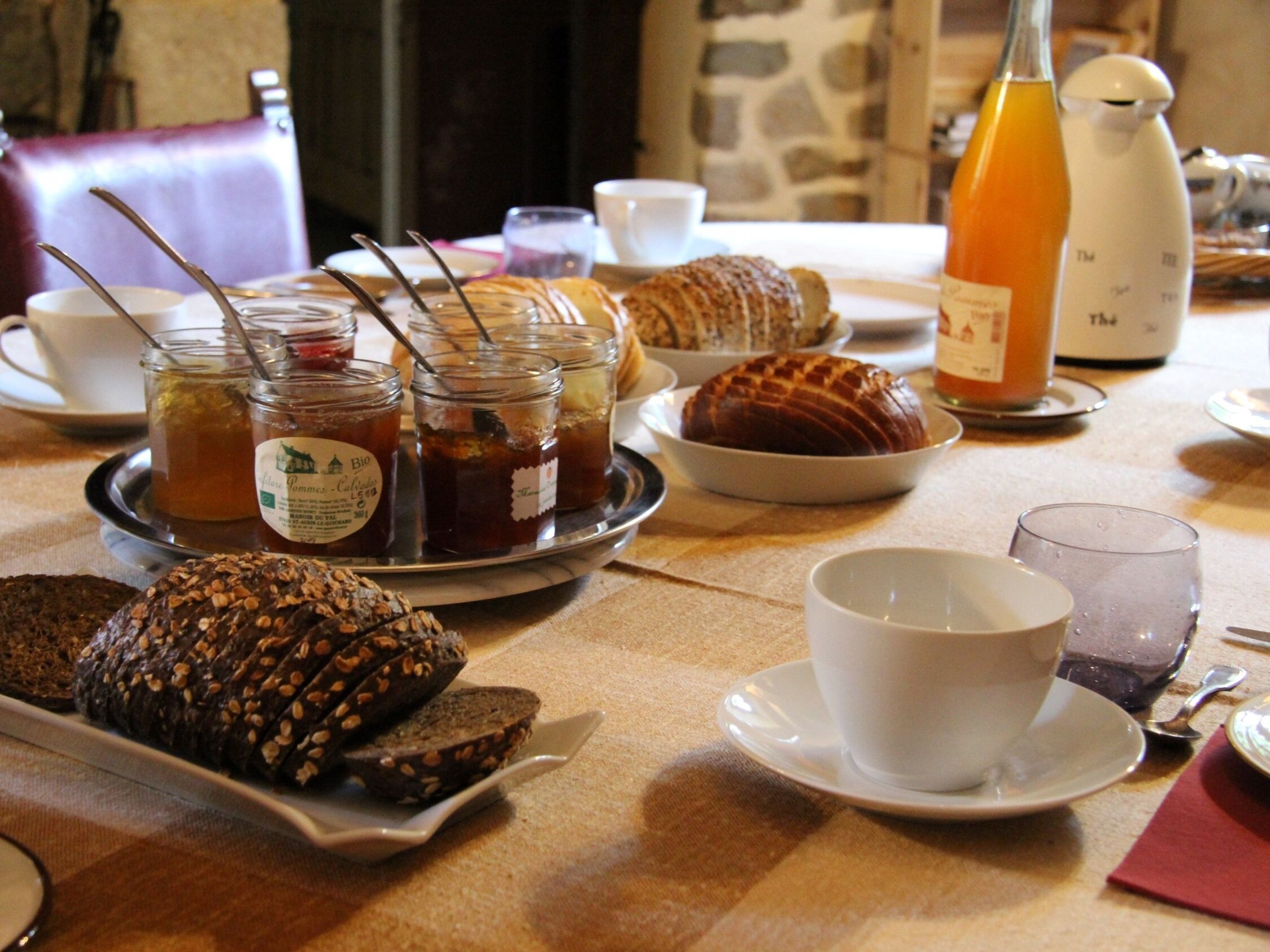 A breakfast setting with bread, pastries, and beverages on a table.
