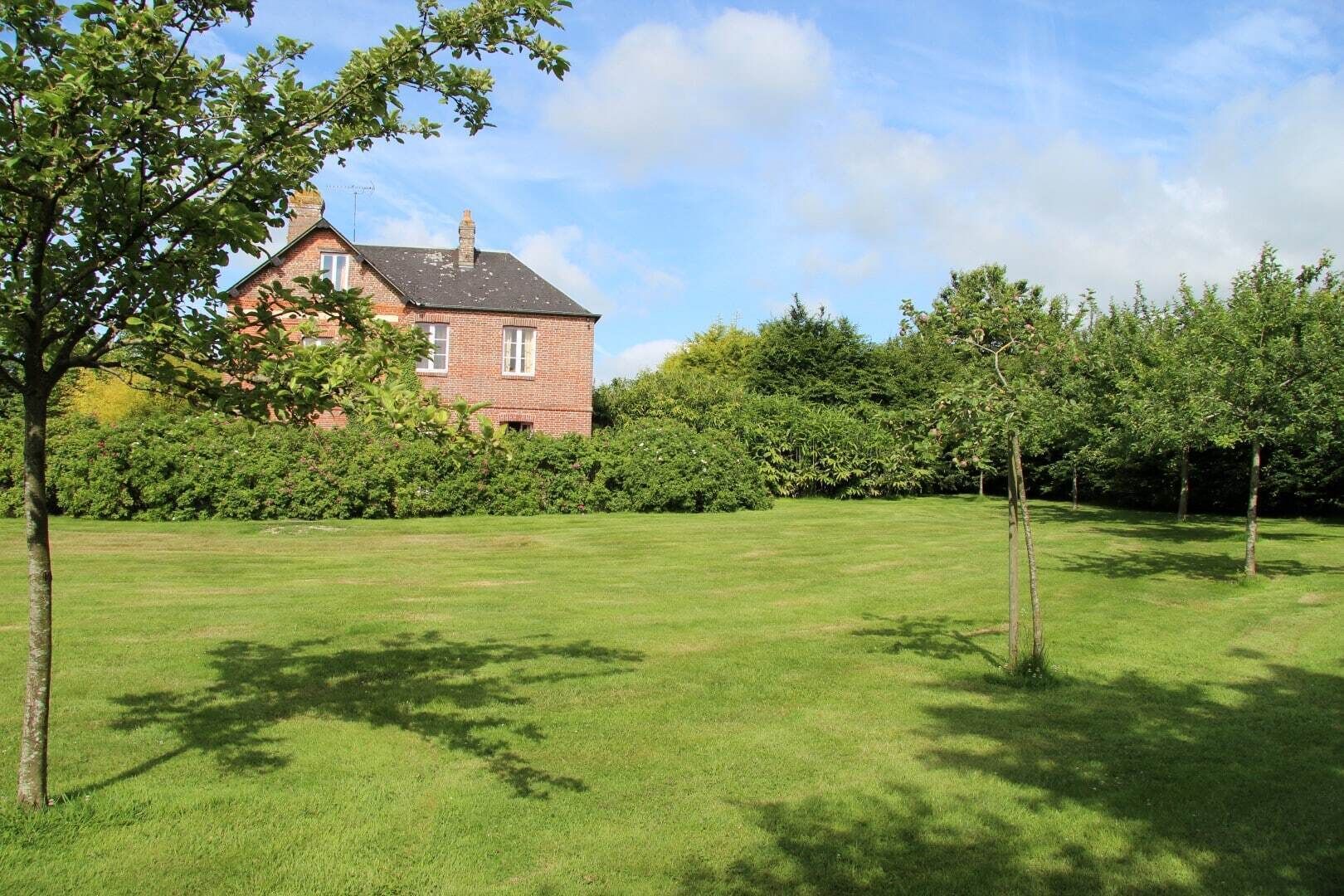 A large, open grassy area with a brick house in the background.