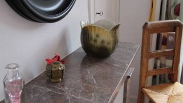 Un plan de travail en marbre agrémenté d’un bol décoratif, d’une petite figurine et d’une bouteille en verre.