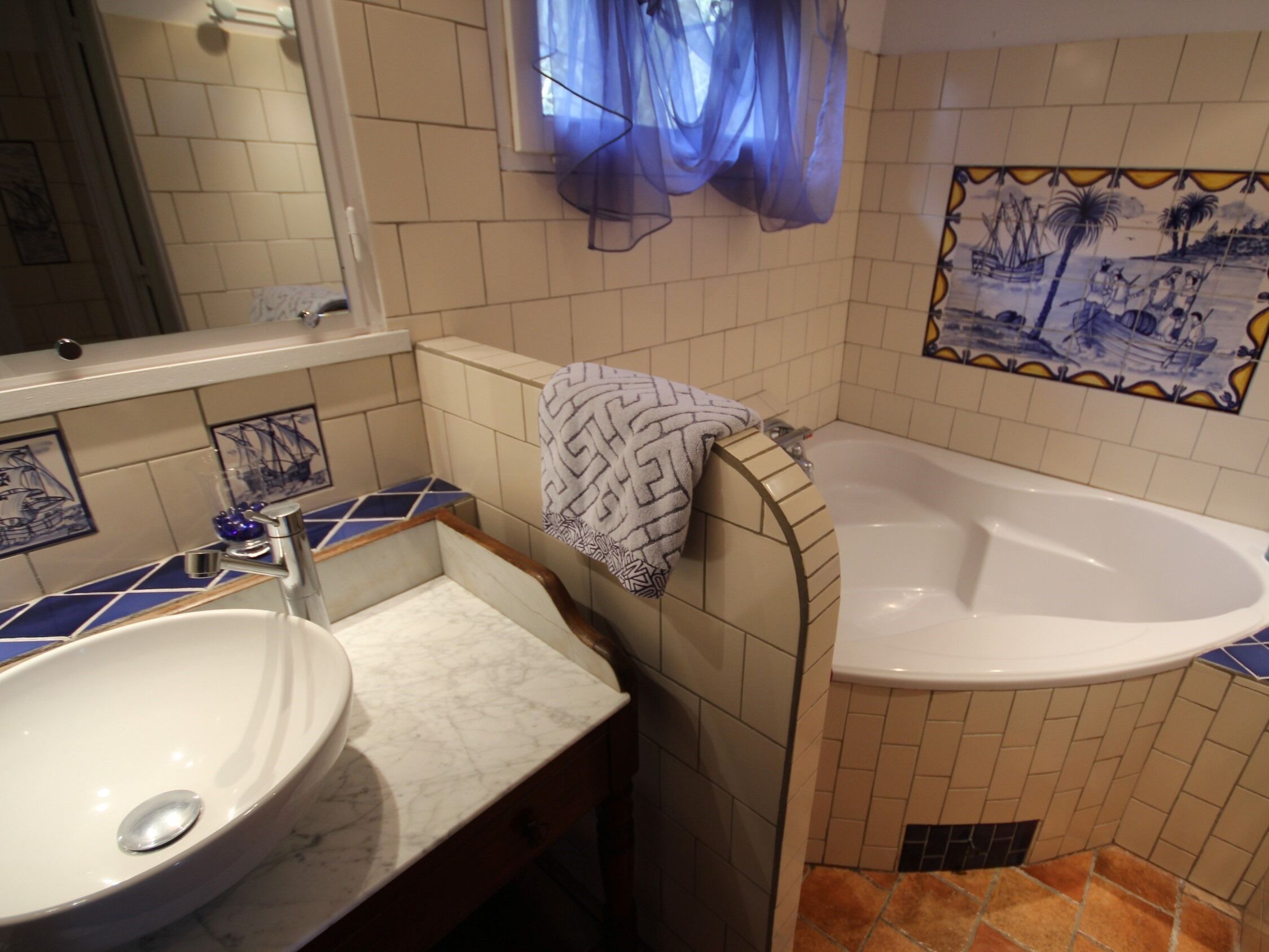 Un baño con lavamanos, espejo, bañera y azulejos decorativos.