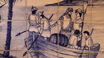 A tiled wall with a maritime scene depicting people in a boat, palm trees, and a bird in the sky.