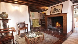 A traditional room with a fireplace, wooden furniture, and a patterned rug. - Le Pommenial de la Hérissonnière (Saint-Aubin-de-Bonneval)