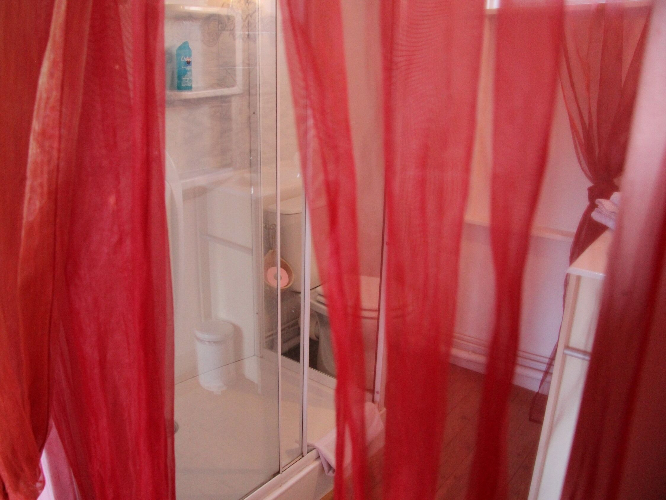 A bathroom with a glass shower enclosure, a toilet, and a sink.