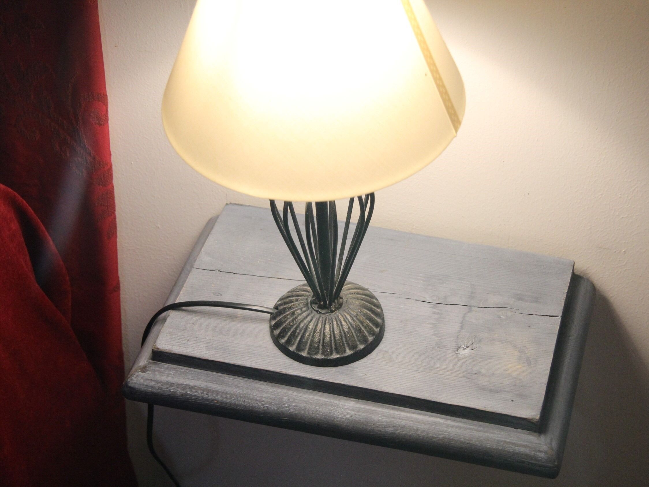 Une lampe de table avec un abat-jour blanc, posée sur une table de chevet en bois.