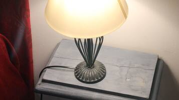 Une lampe de table avec un abat-jour blanc, posée sur une table de chevet en bois.
