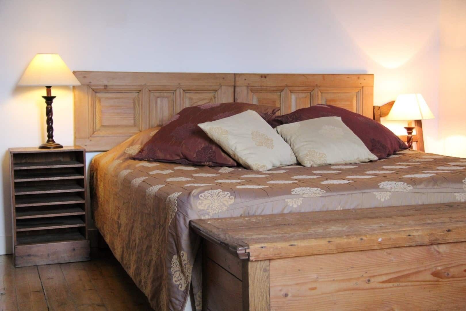 A wooden bed with a headboard, two bedside lamps, and a wooden nightstand with a lamp.
