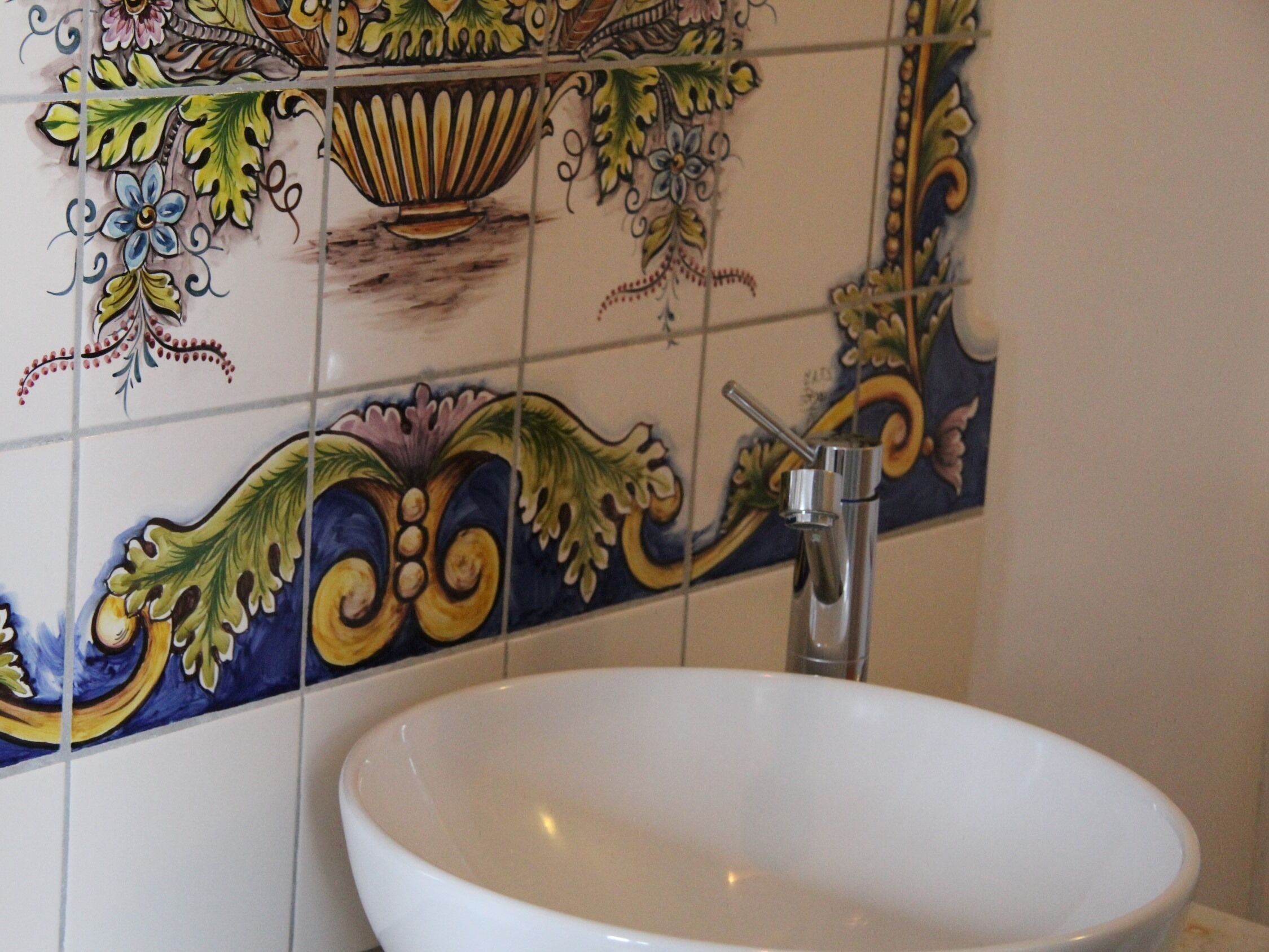 A bathroom with a white sink and a decorative tile backsplash.