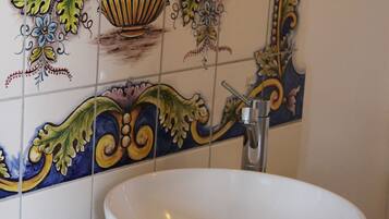 A bathroom with a white sink and a decorative tile backsplash.