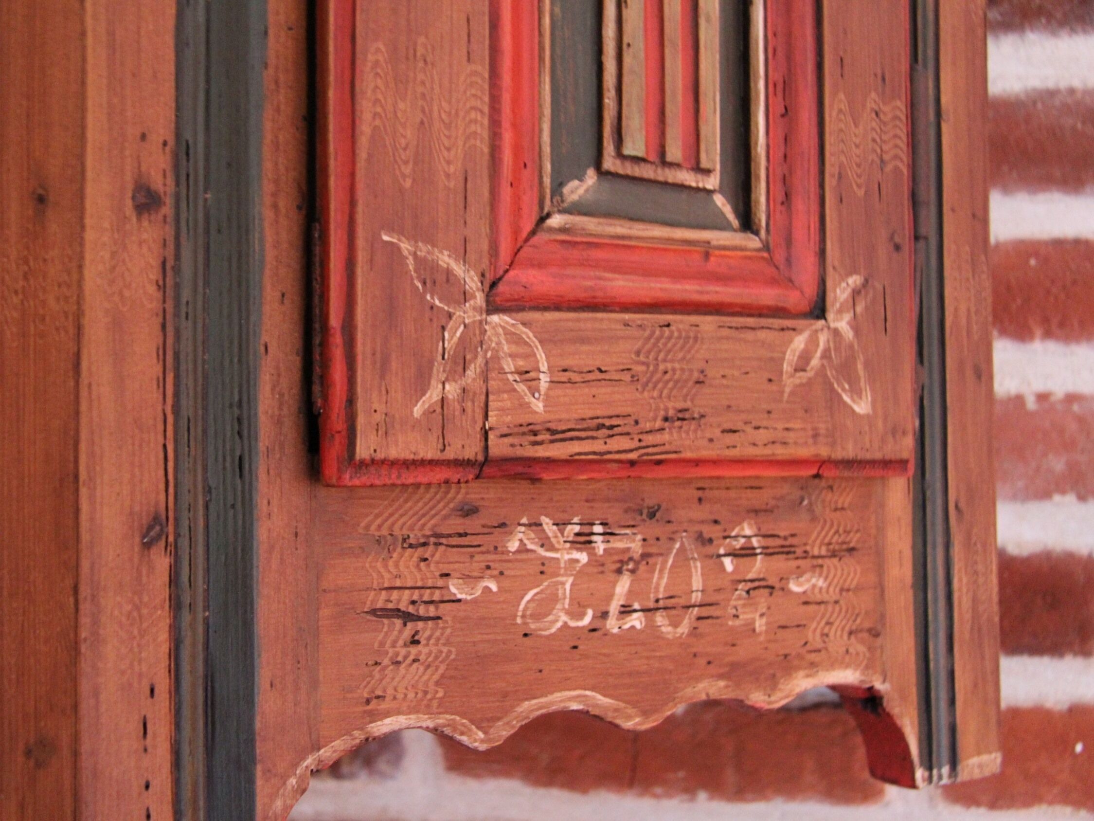A wooden door with carved figures and a decorative panel.