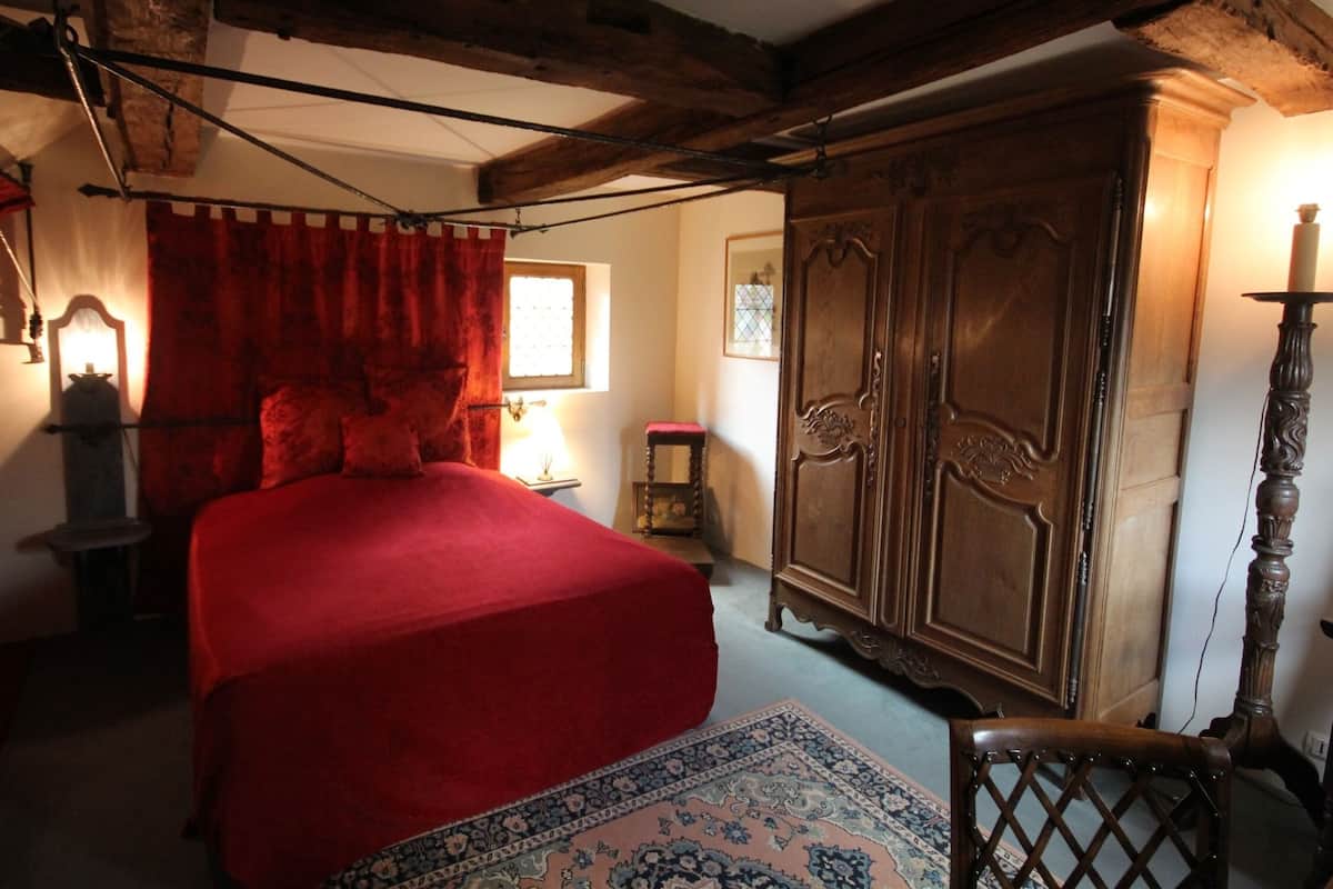 Una habitación con una cama grande, un armario de madera y una silla.