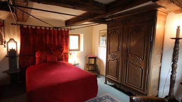 A room with a large bed, wooden wardrobe, and a chair.