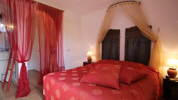 Una camera da letto con un letto grande, una testiera in legno, un comodino con una lampada e una finestra con tende.