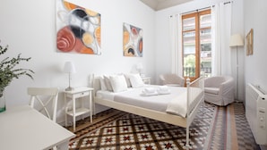 A hotel room with a bed, a desk, a chair, a radiator, and artwork on the walls. - CasaNova Guest House (Barcelona)