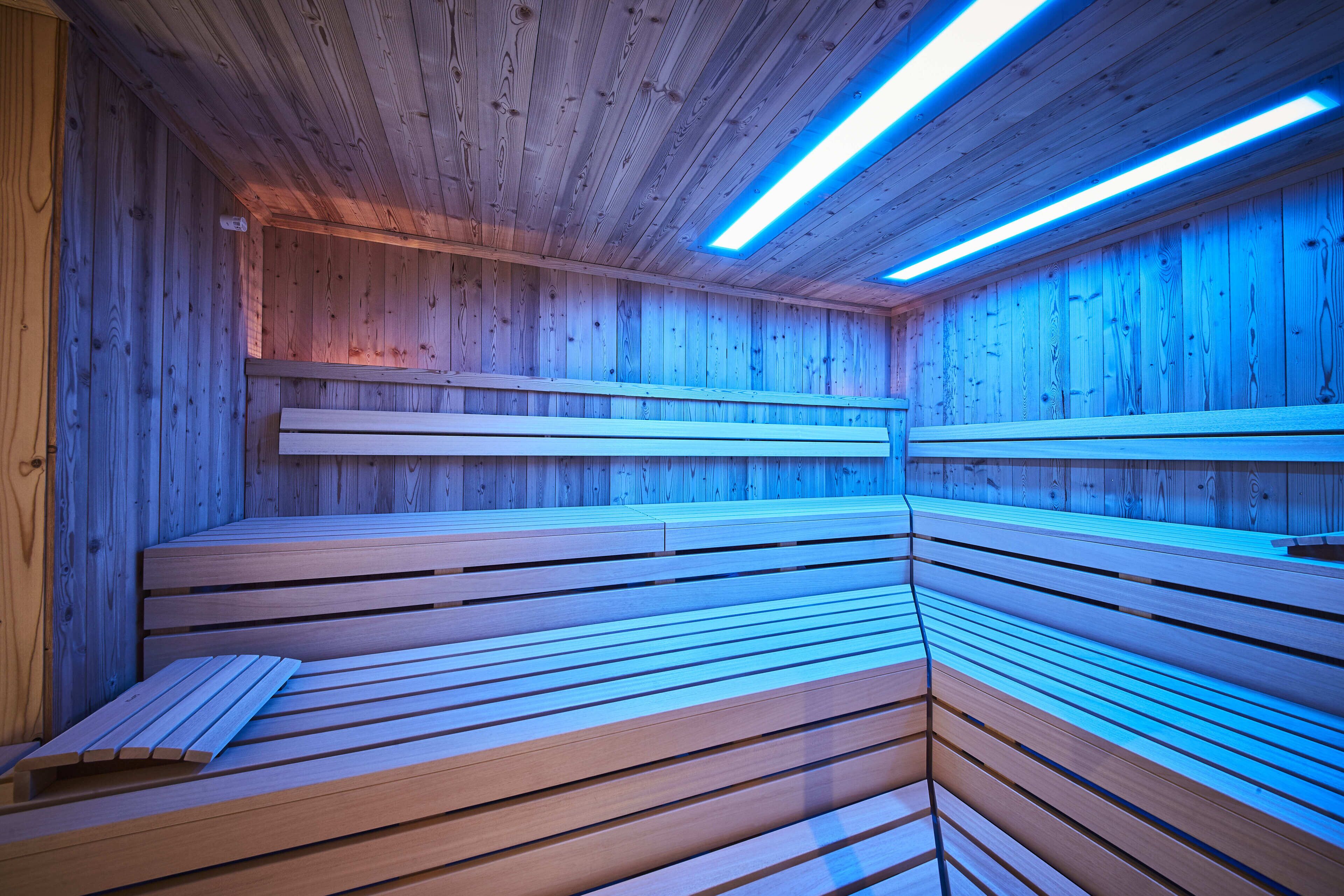 Una sauna con bancos de madera e iluminación azul.