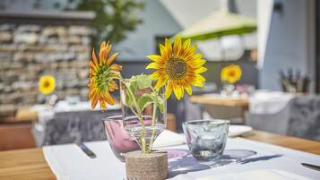 Ein Esstisch mit Kerzenständer, einer Glasvase mit Sonnenblume und einer Glasbowl.