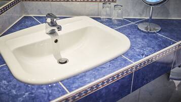 Un baño con lavamanos blanco, encimera de mármol azul y espejo con marco redondo.