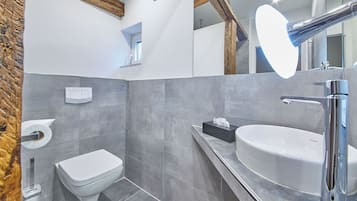 Een moderne badkamer met toilet, wastafel en spiegel.