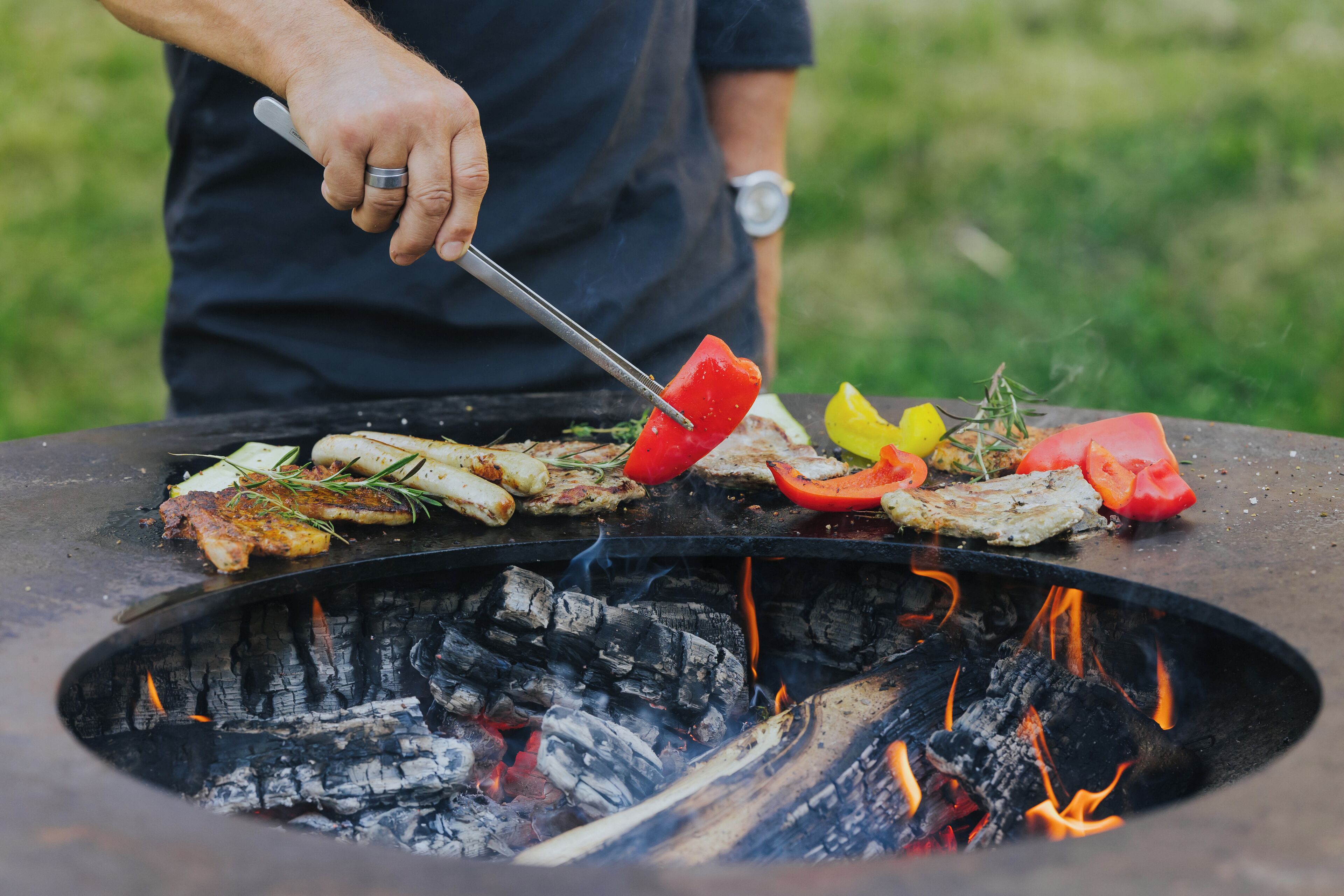 A grill with various meats and vegetables being cooked.