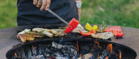 Uma churrasqueira com diversos tipos de carne e vegetais sendo preparados.