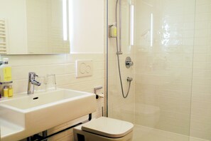A bathroom with a white sink, mirror, and toilet.