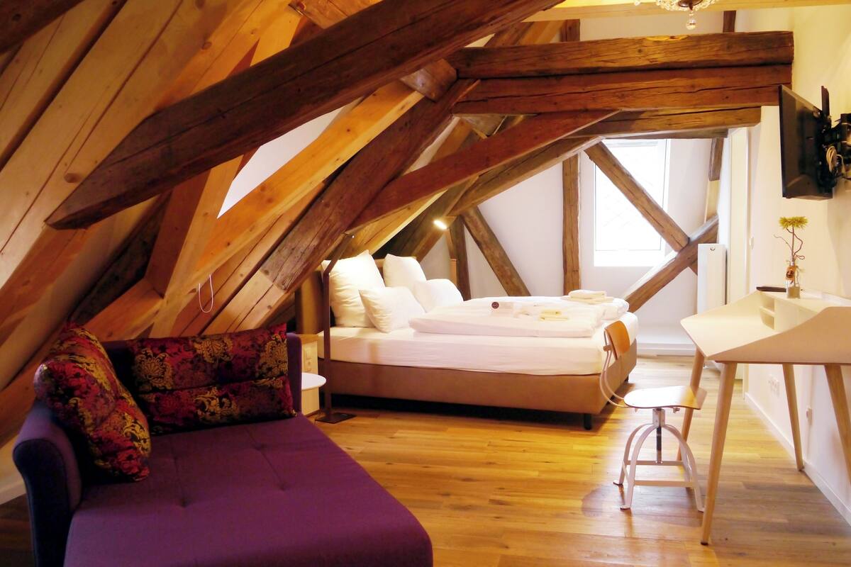 Une chambre à coucher avec un lit, un canapé violet et un bureau avec une chaise.