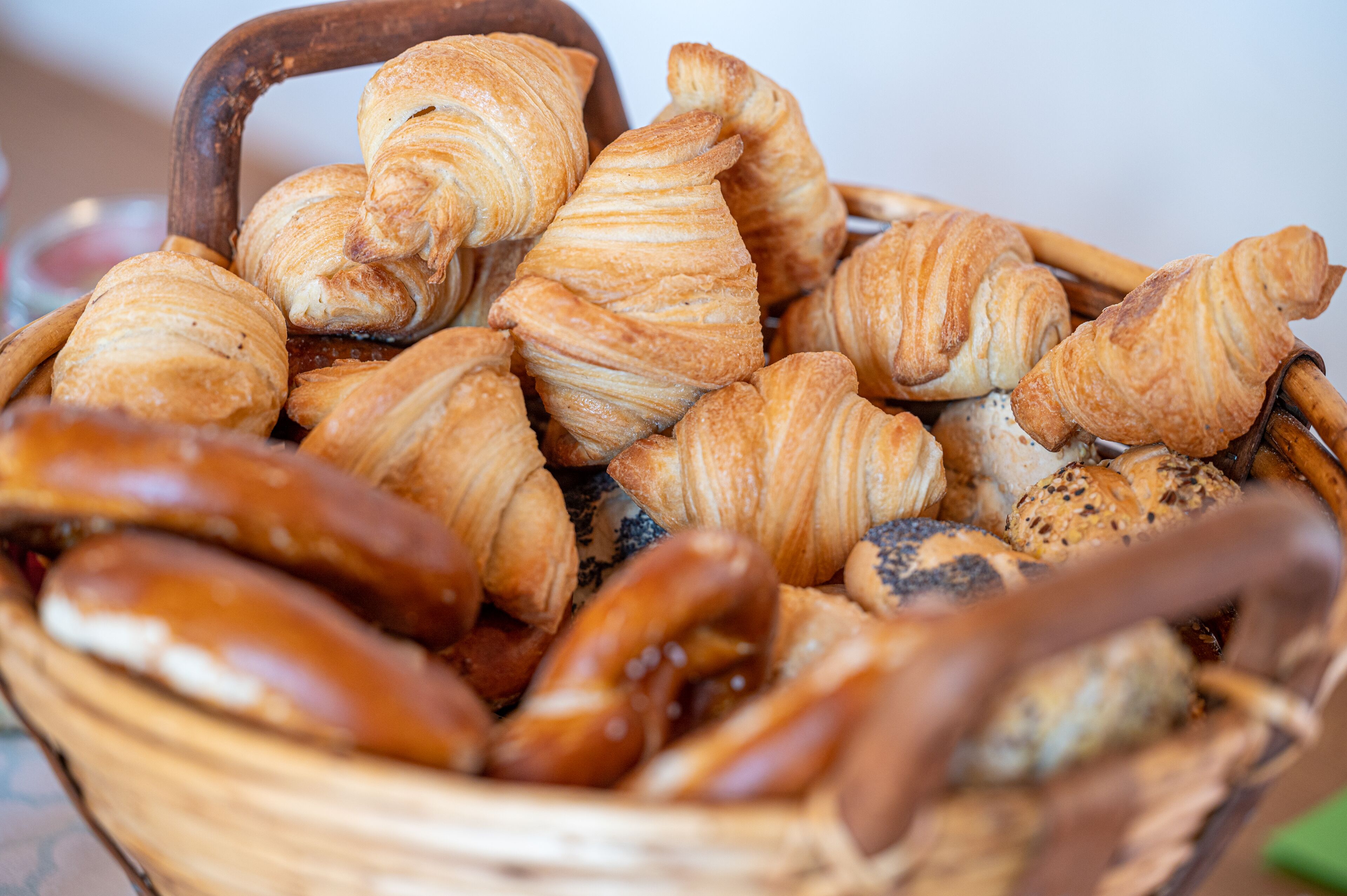 Una cesta llena de productos horneados varios, como croissants y pretzels.