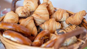 Una cesta llena de productos horneados varios, como croissants y pretzels.