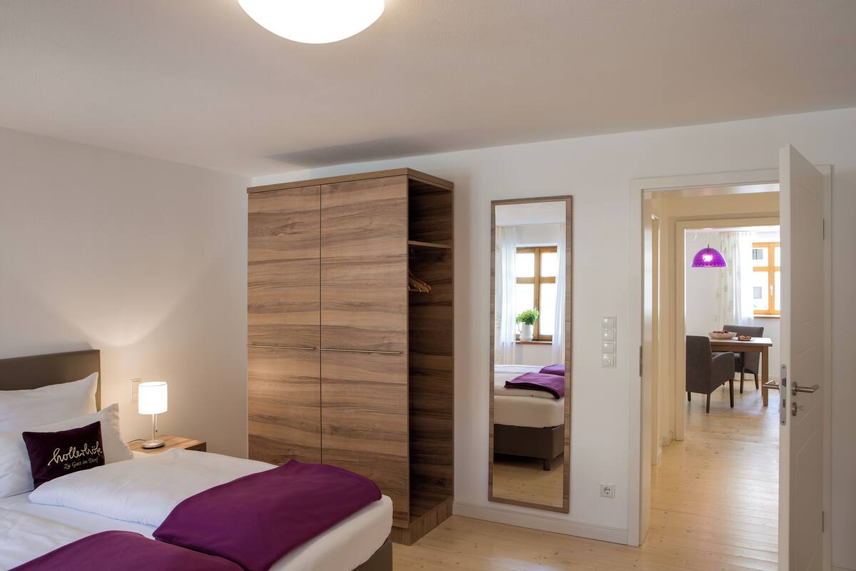 Une chambre à coucher comprenant un lit, une armoire, une table de chevet et un miroir.