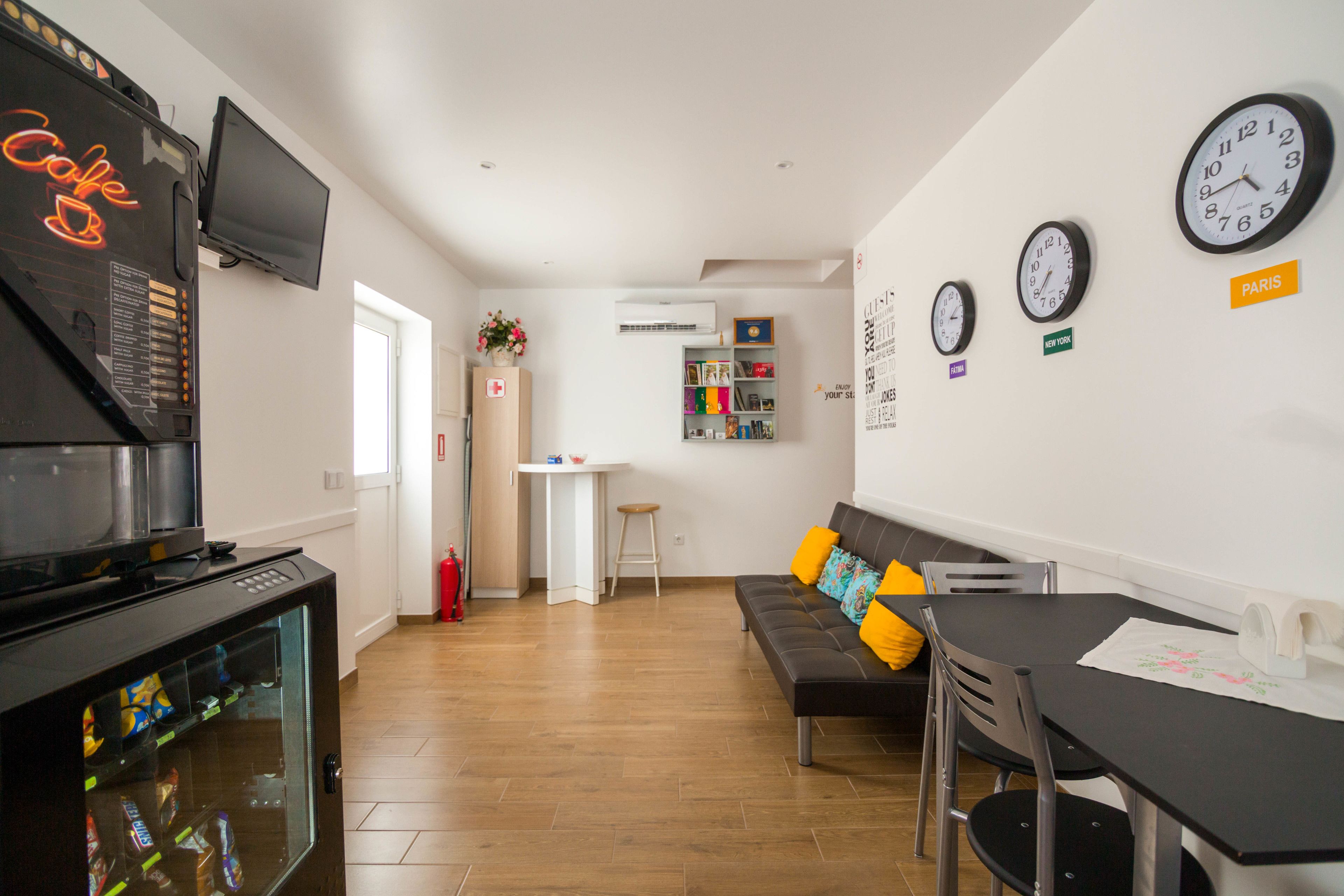 A modern living room with a sofa, a dining table, and a TV mounted on the wall.