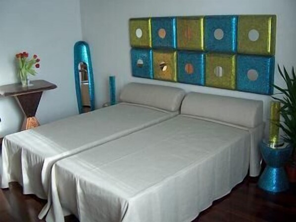 A room with a bed, a small table with a vase of flowers, and a decorative wall panel. - Domus Orsoni (Venice)