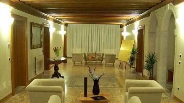 A hotel lobby with a reception desk, two sofas, a coffee table, and a painting on easel. - Domus Orsoni (Venice)
