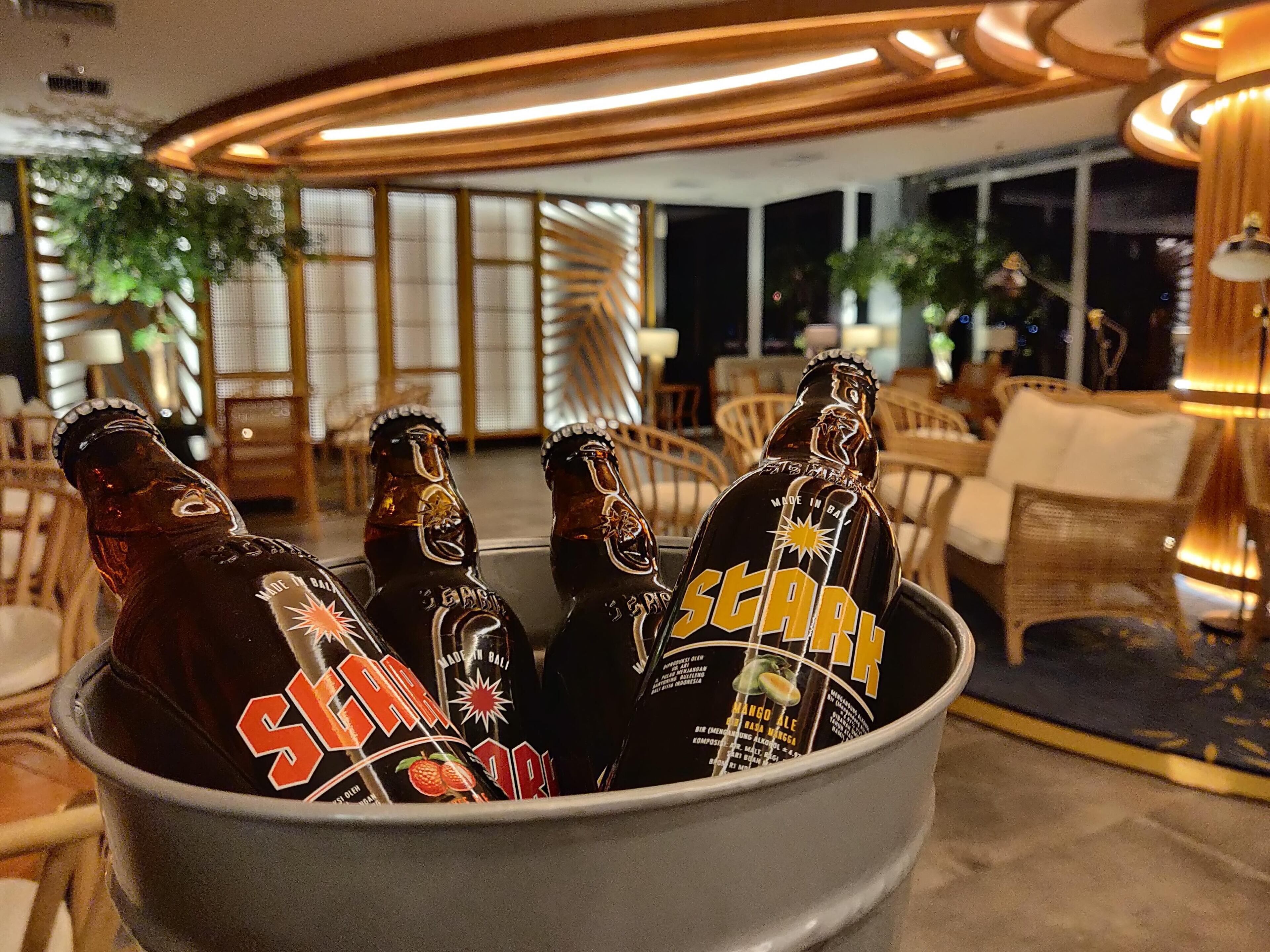 Un seau rempli de bouteilles de bière Star, dans un intérieur bien éclairé, avec des meubles en bois et de grandes fenêtres.