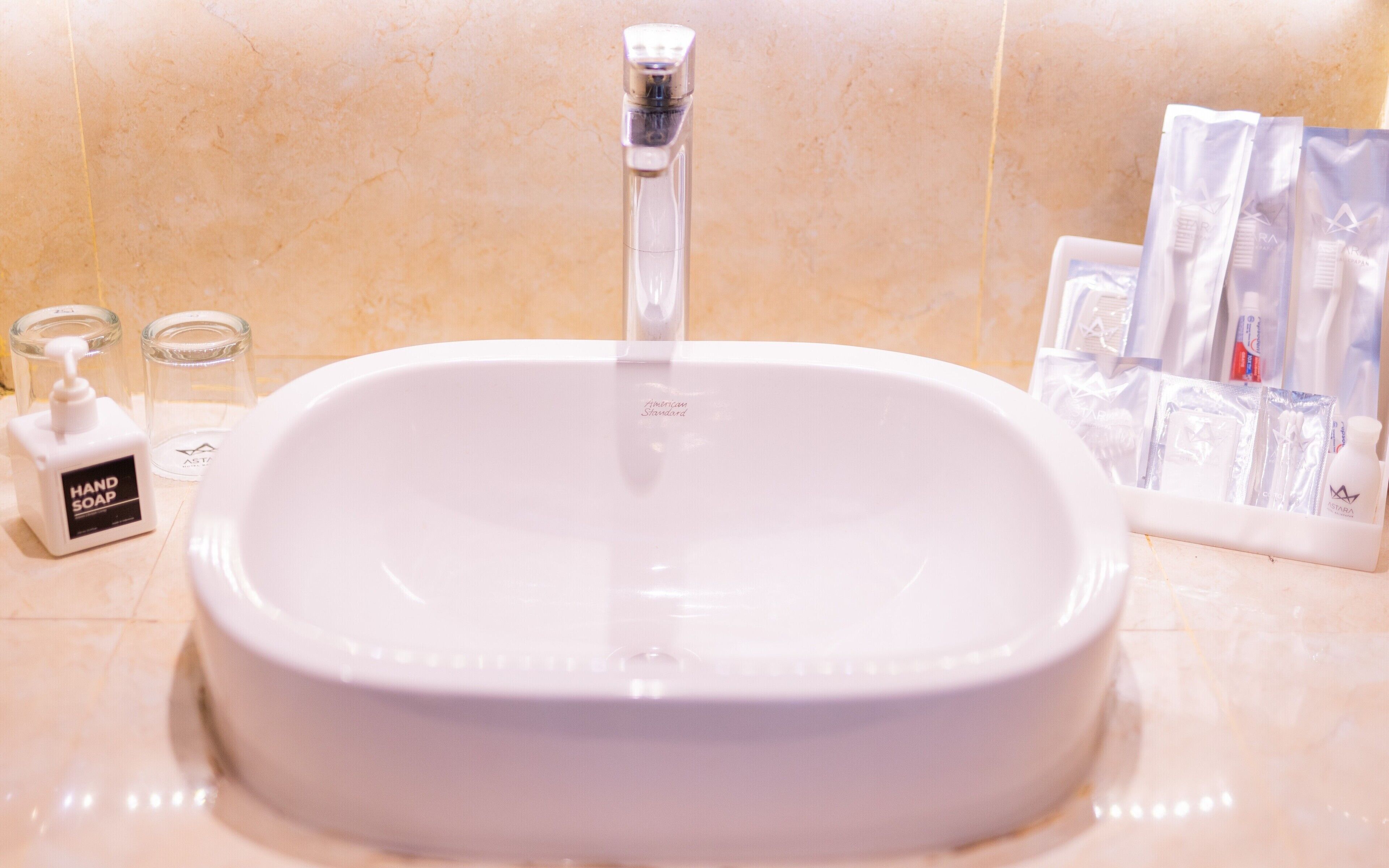 Un lavabo de salle de bain avec un robinet, un distributeur de savon liquide et des articles de toilette.