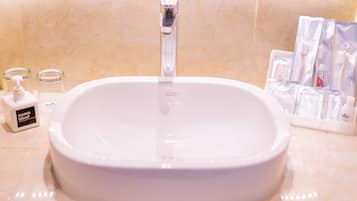 Un lavabo de salle de bain avec un robinet, un distributeur de savon liquide et des articles de toilette.