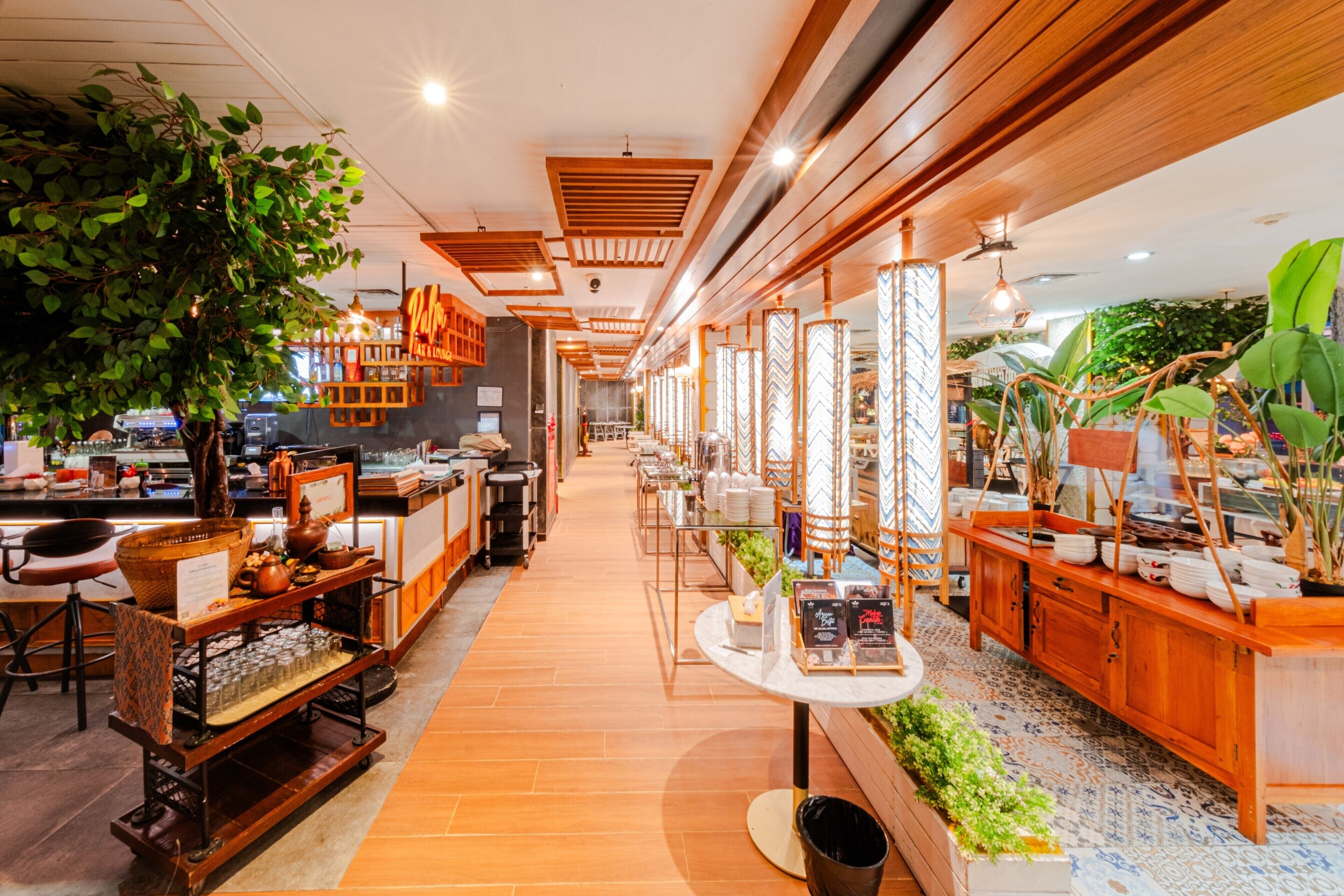 Un restaurante con una barra larga, decoración de madera y plantas en macetas.