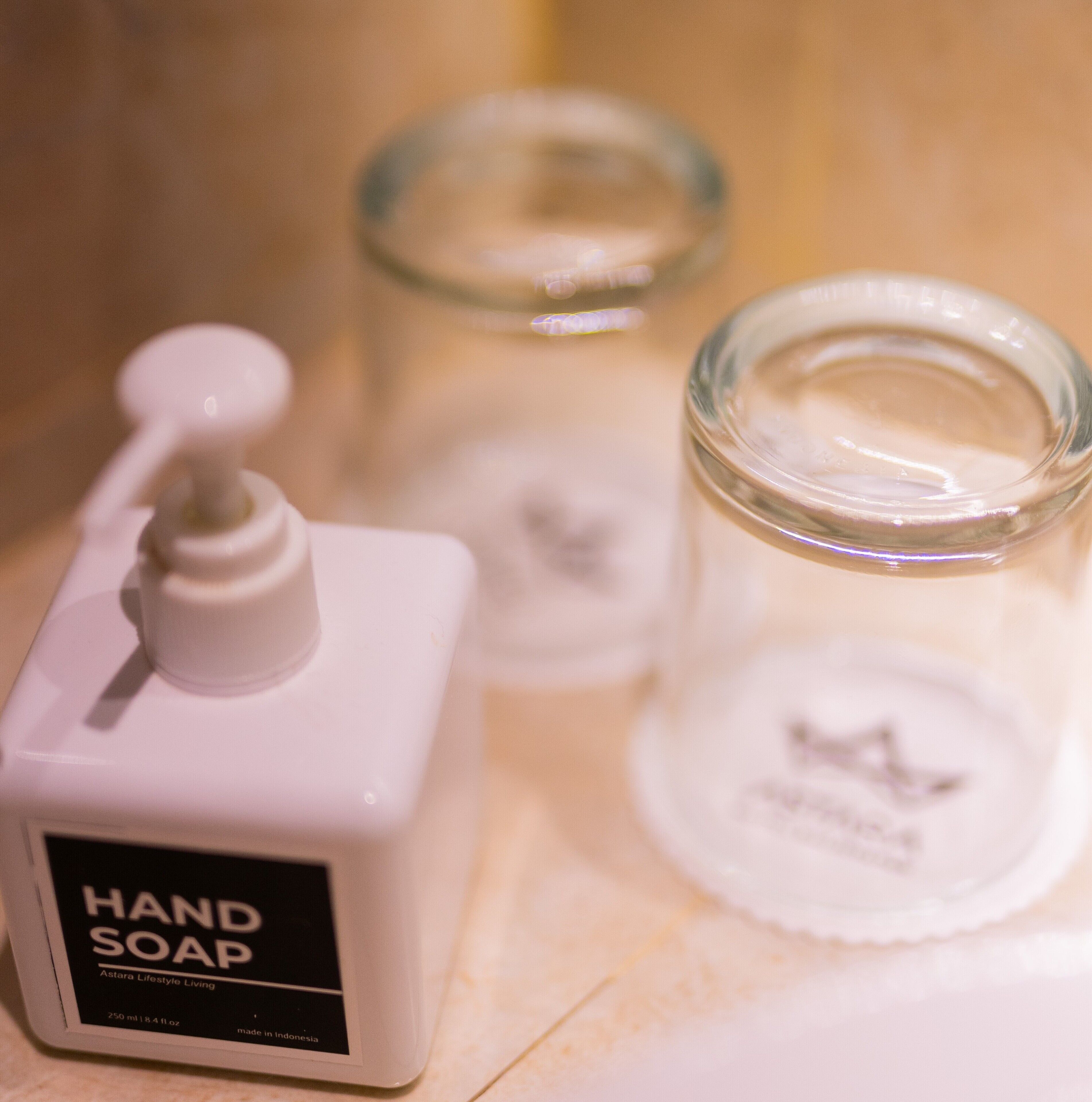 A bottle of hand soap and two glass containers on a surface.