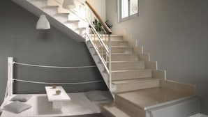 Una escalera moderna de diseño minimalista, una mesita con un jarrón y vistas al piso superior.