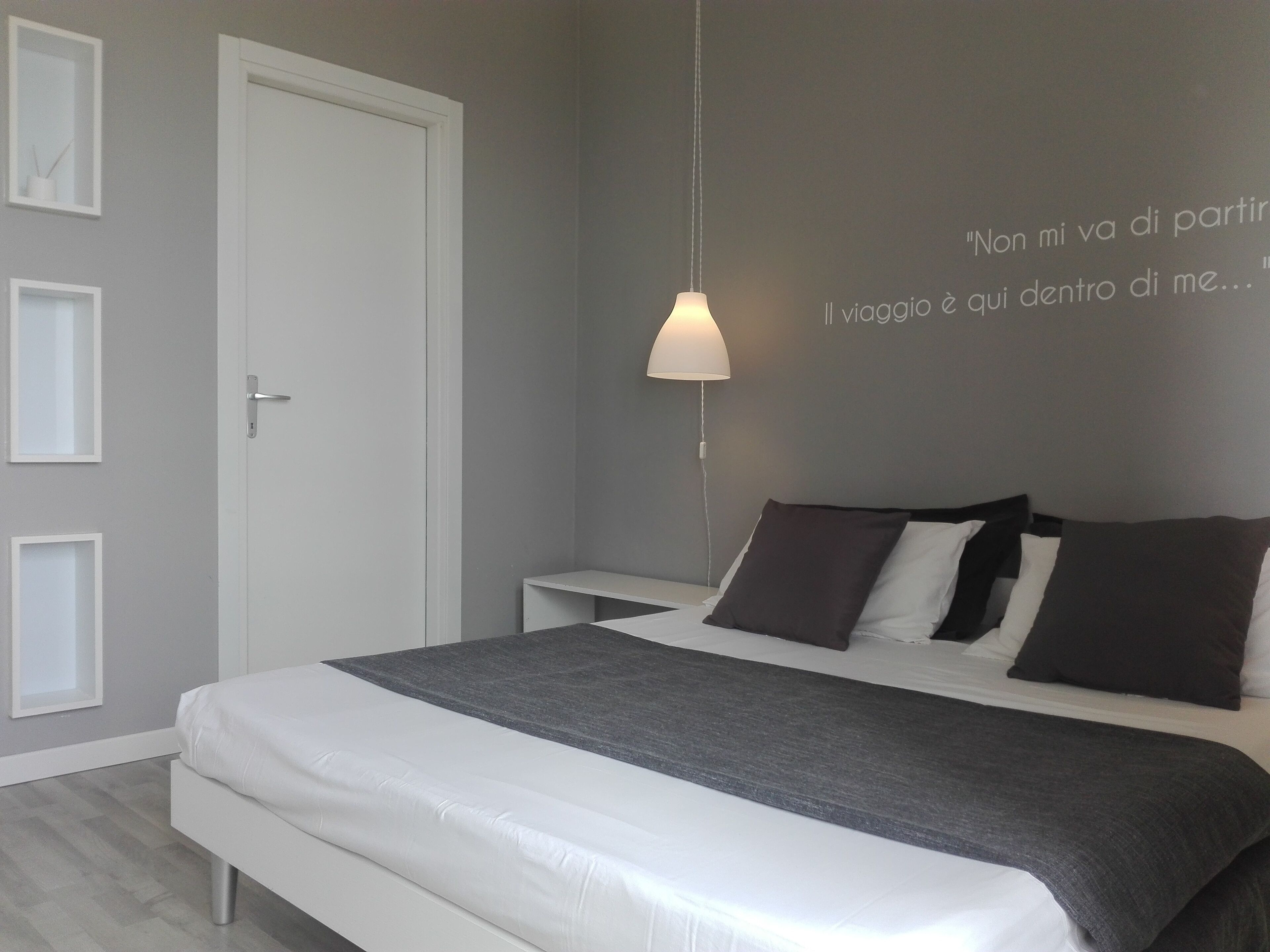 A modern bedroom with a bed, bedside tables, and a wall with a quote.