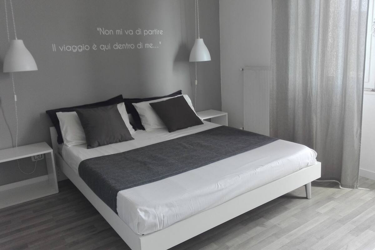 Un dormitorio moderno con una cama, mesitas de noche y una cita en la pared.