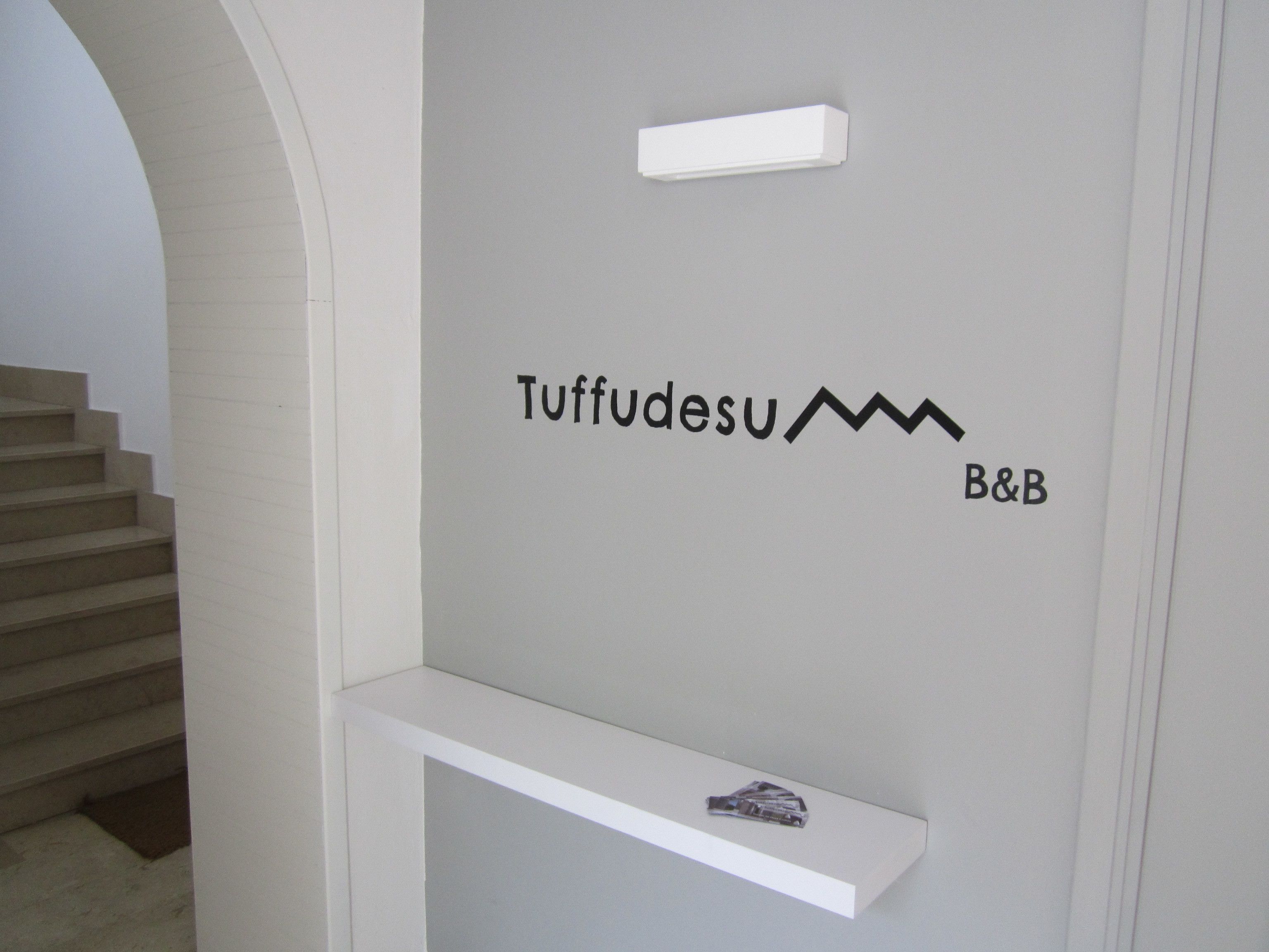 Un escalier menant à un palier où est affiché un panneau indiquant « Tuffudesu B&B ».