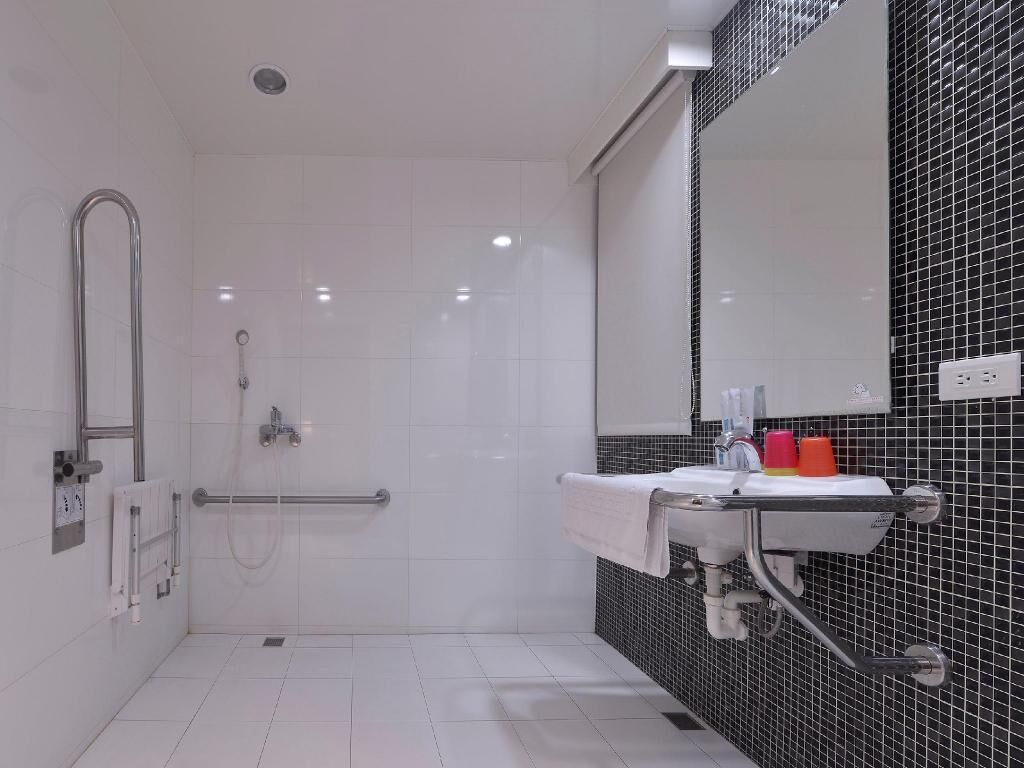 Une salle de bain moderne avec une douche à l’italienne, un lavabo avec un miroir et un sol carrelé.