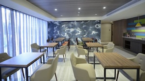 A modern restaurant with wooden tables and chairs, a large mural on the back wall, and a bright ceiling with recessed lighting. - Ximen Hotel (Taipei)