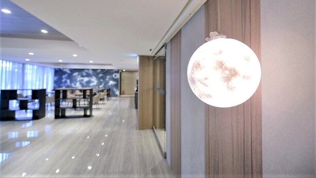 A modern hotel lobby with a polished floor, a reception desk, and a large wall-mounted spherical light fixture. - Ximen Hotel (Taipei)
