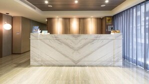 A reception area with a marble reception desk, wooden panel walls, and a large window with curtains. - Ximen Hotel (Taipei)