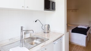 Una cocina moderna con armarios blancos, un lavamanos de acero inoxidable y un microondas.