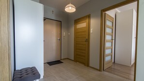 A hallway with a bench, wooden doors, and a light fixture. - Rent a Flat Apartments - Jana Pawla II (Gdansk)