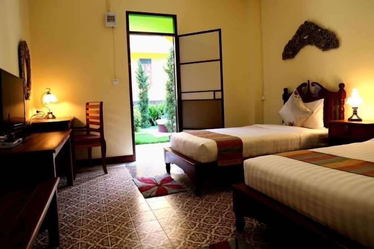 Une chambre d’hôtel avec deux lits, un bureau, une chaise et une vue sur l’extérieur.